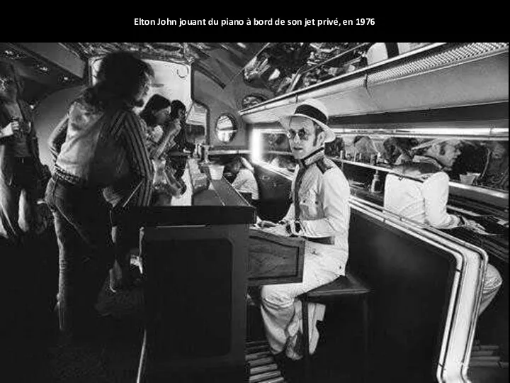Elton John jouant du piano à bord de son jet privé, en 1976